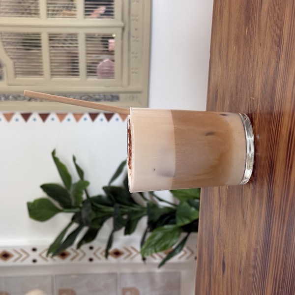 Un chai latte glacé sur une table en bois, devant le mur peint du club