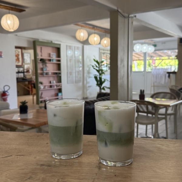 Deux matcha lattes glacés posés sur une table, la salle en arrière-plan