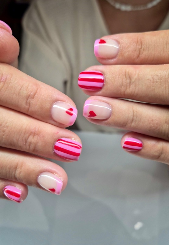 Rayures roses et rouges et petits cœurs sur ongles courts