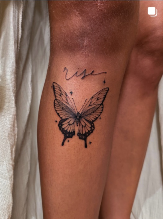 Papillon fineline surmonté du mot « rise » en lettering, sur un mollet