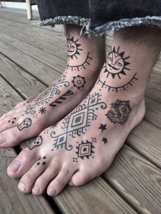 Deux pieds couverts d'ornemental : soleils, motifs géométriques et têtes de mort